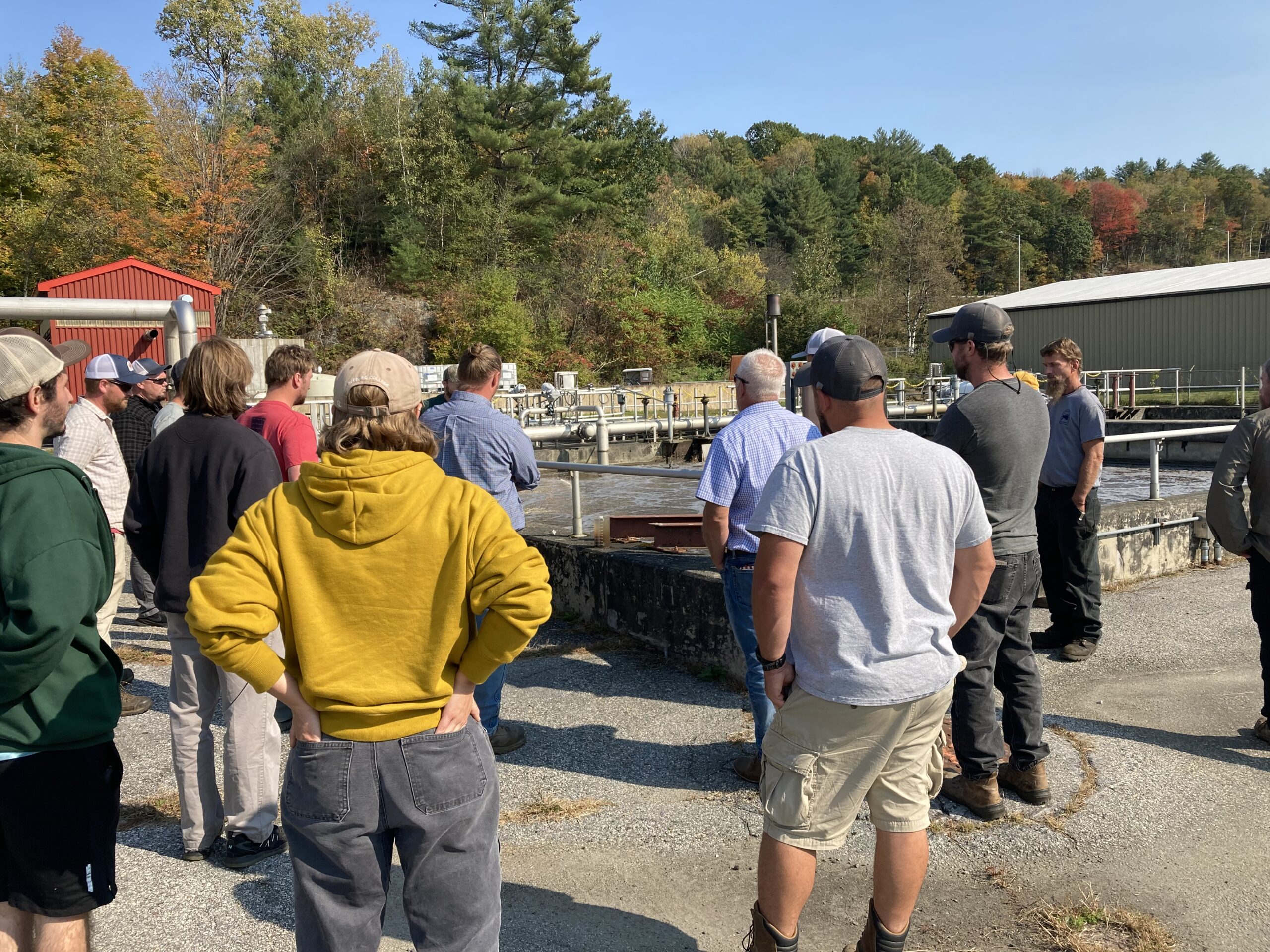 A number of people are standing looking at an aeration basin.