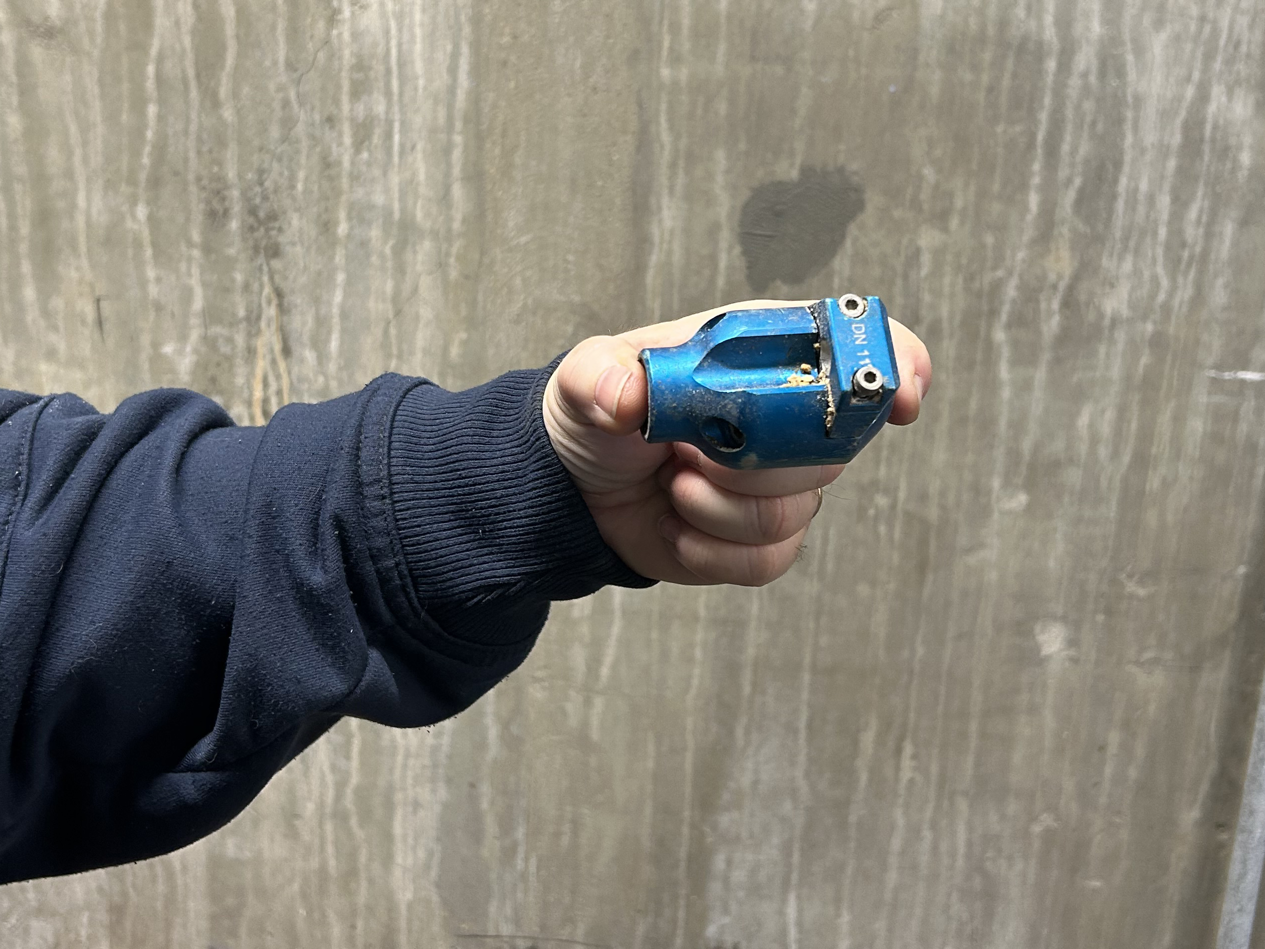 A man with a gray mustache stands by a control panel, pointing at the monitor.
